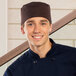 A smiling chef wearing an Uncommon Brown chef skull cap with hook and loop closure.