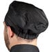 A man wearing a black Uncommon Chef Kool Mesh chef hat.
