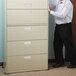 A man wearing black pants uses Master Caster Mighty Mighty Movers to push a white file cabinet.