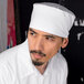 A man with a beard wearing a white Uncommon Chef mesh top chef skull cap.