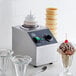 A Carnival King sauce topping bottle warmer with a glass of ice cream and chocolate topping on a table.