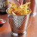 A hand holding a Vollrath mini stainless steel bucket filled with french fries.