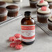 A bottle of Nielsen-Massey Pure Peppermint Extract next to cupcakes with a peppermint on top.