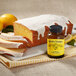 A loaf of lemon pound cake with a bottle of Nielsen-Massey Pure Lemon Paste on a table.