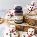 A snowman shaped cookie with white frosting and a bottle of Nielsen-Massey Madagascar Bourbon Vanilla Paste.