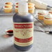 A bottle of Nielsen-Massey Mexican Vanilla Extract next to cupcakes with white frosting.