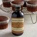 A bottle of Nielsen-Massey Pure Coffee Extract next to chocolate cupcakes.