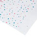 A white paper table cover with red and blue confetti and squares.