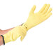 A pair of yellow Cordova cut resistant gloves with black wrist bands on a pair of hands.