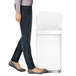 The lower half of a person's body in jeans walking next to a simplehuman white stainless steel rectangular front step-on trash can.