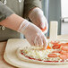 A person wearing Noble Products disposable gloves preparing a pizza.