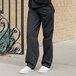 A person wearing Uncommon Chef black and white pinstripe chef pants.