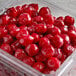 A plastic container of IQF pitted tart red cherries on a table.