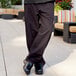 A person wearing Uncommon Chef pinstripe chef pants with black shoes.