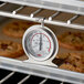 A Cooper-Atkins oven thermometer with a metal handle in an oven.