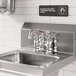 A stainless steel deck-mounted faucet with 4-inch centers and a 6-inch swing spout installed on a commercial sink.