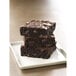 A stack of Ghirardelli double dark chocolate brownies on a white plate.