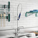 A white kitchen sink with a Waterloo pre-rinse faucet and a rack of dishes above it.