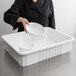 A woman in a black jacket holding a white bowl over a white Metro Divider Tote Box.