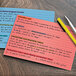 A group of Oxford ruled index cards in assorted colors with writing on them.