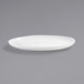 A white Front of the House Harmony coupe oval porcelain plate on a gray surface.