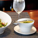 A bowl of soup with a Harmony stainless steel demitasse spoon on a table.