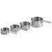 A row of four silver stainless steel Vollrath measuring cups with handles.