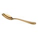 A gold-colored metal spoon with a smooth, curved handle and a reflective finish, shown on a white background.
