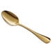 An Acopa Vernon gold stainless steel oval bowl spoon with a long handle.