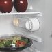 A Hamilton Beach black compact refrigerator with a bowl of salad and apples inside.