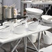 A white rectangular porcelain platter on a table with white bowls and utensils.