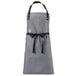 A grey apron with black straps and a black belt.