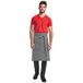 A man wearing a navy and white railroad stripe Mercer Culinary Bistro Apron with 3 pockets.