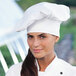 A woman wearing a white Uncommon Chef chef's hat.