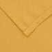 A close up of a yellow rectangular fabric table cover with a hemmed edge.