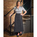 A woman wearing a Mercer Culinary black denim bistro apron standing on a staircase.