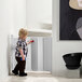 A child playing with a L.A. Baby white auto retractable safety gate in a room.