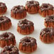 A group of small fluted cakes with chocolate drizzle on top.