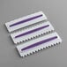 Three white and purple plastic Wilton icing combs.
