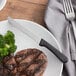 A plate with a steak and broccoli with a stainless steel steak knife on it.