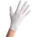 A person's hand wearing a medium Noble Products white nitrile glove.