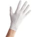 A person's hand wearing a Noble Products white nitrile glove.