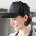 A woman wearing a Henry Segal black cap with mesh back in a professional kitchen.