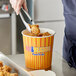 A person using tongs to grab chicken nuggets from a Choice hot food bucket.