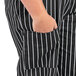 A person wearing Uncommon Chef black and white striped cargo pants with a hand in the pocket.