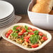 A Carlisle tan melamine rectangular bowl filled with pasta with tomatoes and basil.