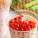 A cup of milk with red and white Bossen Dragon Fruit Bursting Boba.
