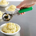 A hand using a Hamilton Beach Green Thumb scoop to serve mashed potatoes into a bowl.