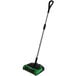 A green and black Bissell Commercial cordless floor sweeper with a handle.