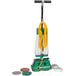 A Bissell Commercial low speed floor machine with a yellow cord and two brushes.